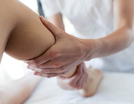 A therapist working through a patient's knee and calf on the treatment table
