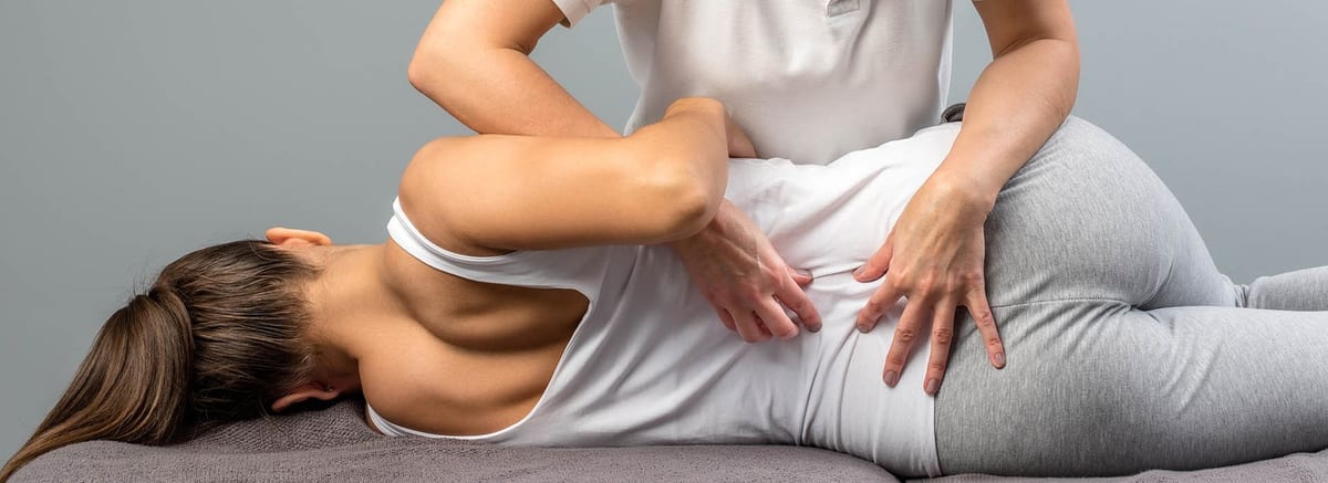 Hands-on treatment along a patient's lower back on the treatment table