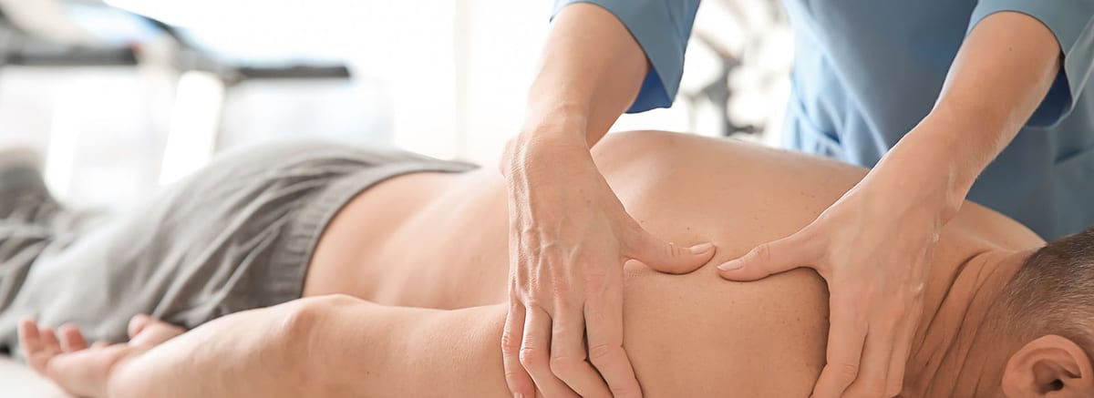 A therapist working along a patient's shoulder and upper back